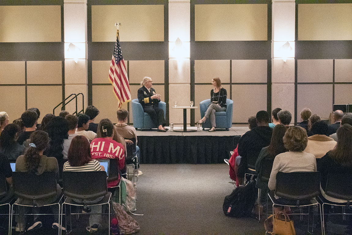 The U.S. Assistant Secretary for Health and a college professor converse on a stage in front of a large crowd